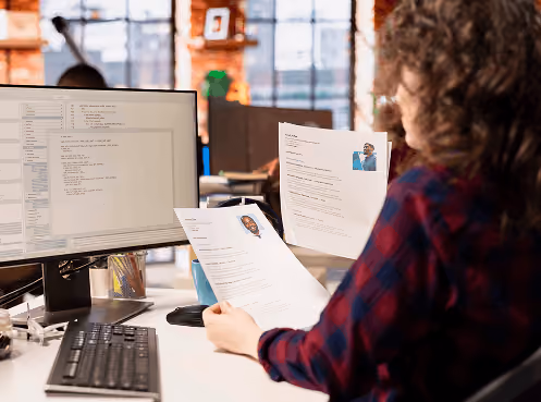 Recruiter reviewing printed resumes with candidate photos