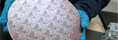 Engineer holding a silicon wafer patterned with semiconductor dies