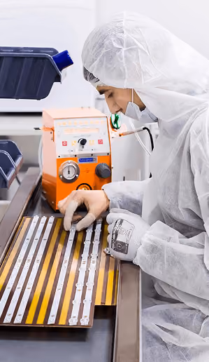 Cleanroom operator inspecting components in a fabrication facility