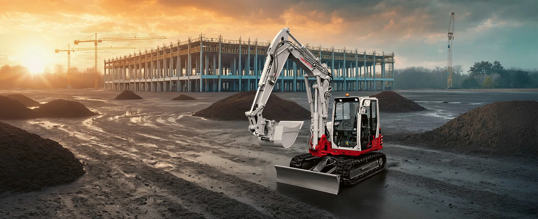 Takeuchi ekskavators būvlaukumā saulrietā.