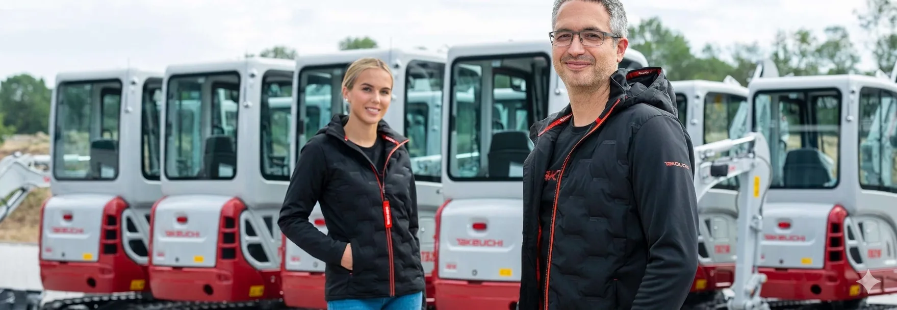 Takeuchi ekskavatori, 2 cilvēki Takeuchi jakās.