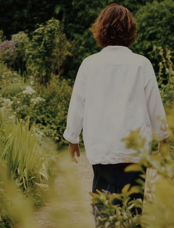 a woman walking on a trail with tall plants