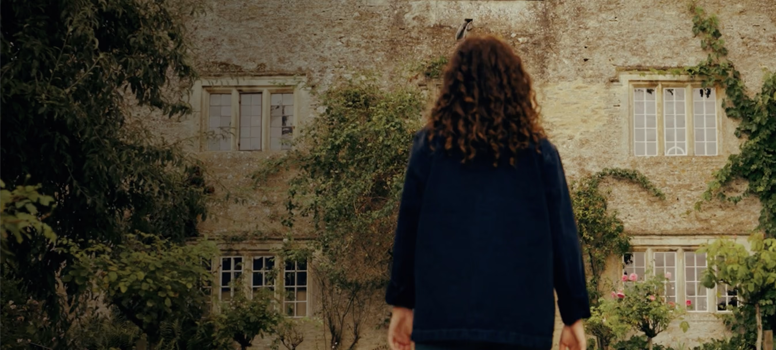 A woman walking with an abandoned building in the foreground