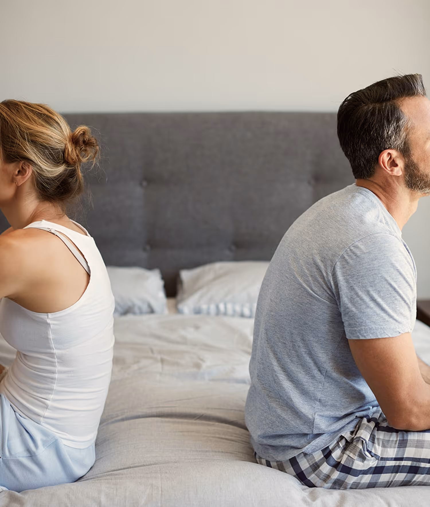 a man and a woman sitting on the bed with their backs to each other