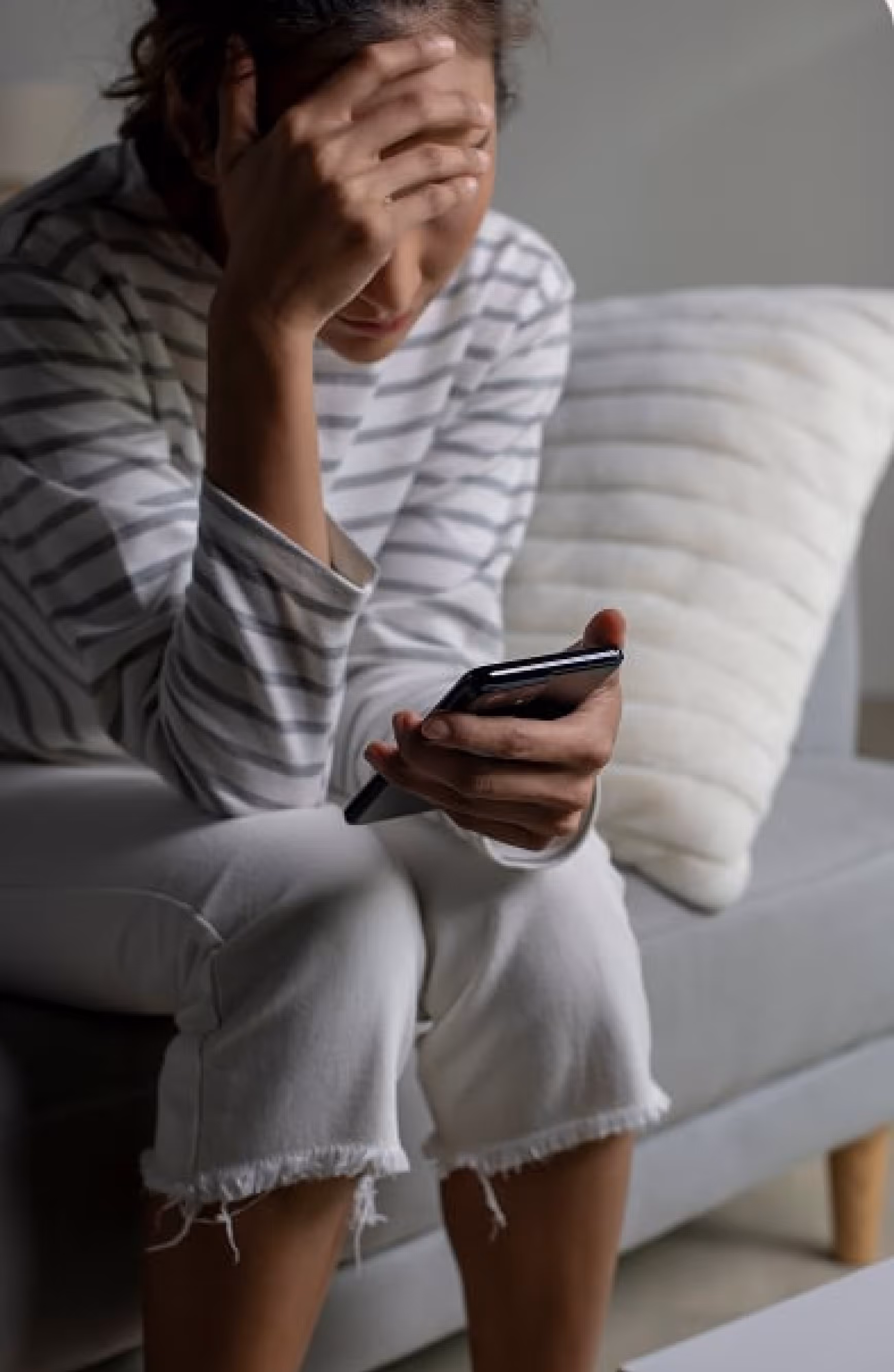 A girl sitting and looking at her phone, looking very sad