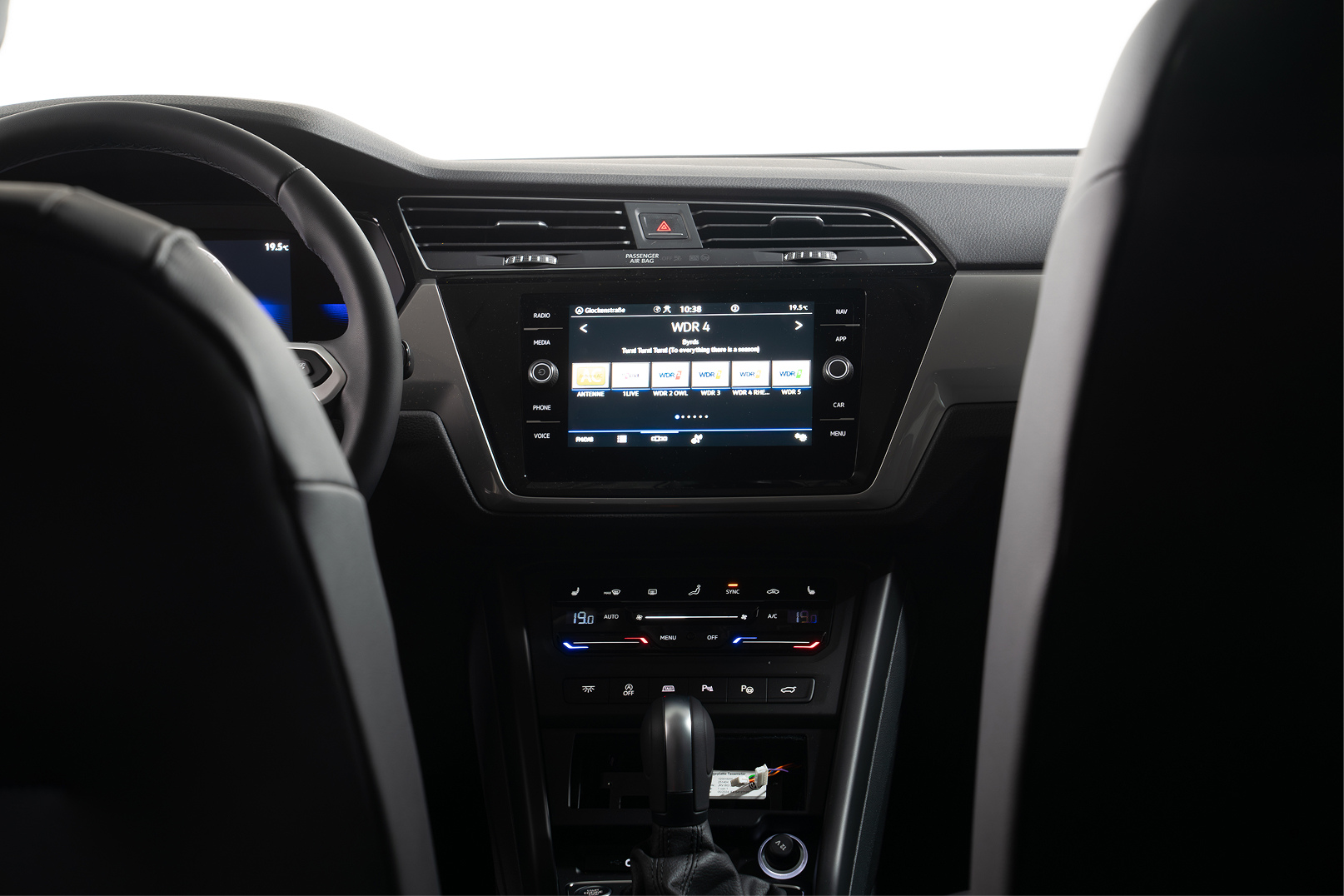 Car dashboard with center touchscreen showing radio station WDR 4 and climate control panel below.
