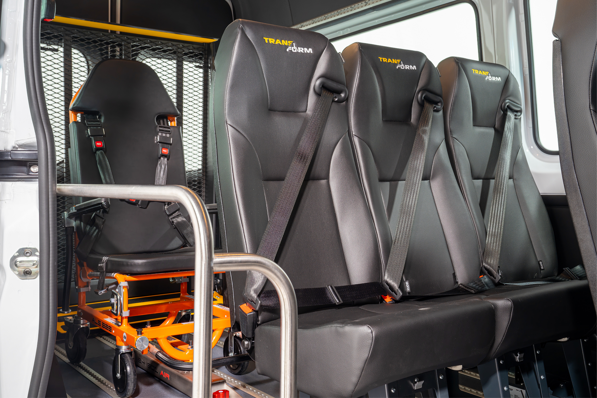 Interior of a vehicle with three black passenger seats and an orange wheelchair secured behind them.