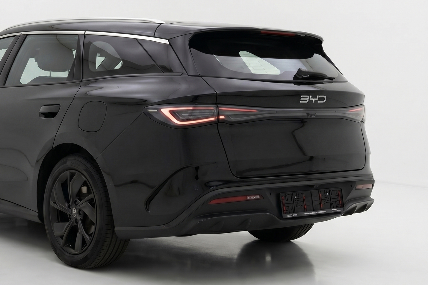 Rear view of a sleek black BYD electric car with distinctive LED tail lights.