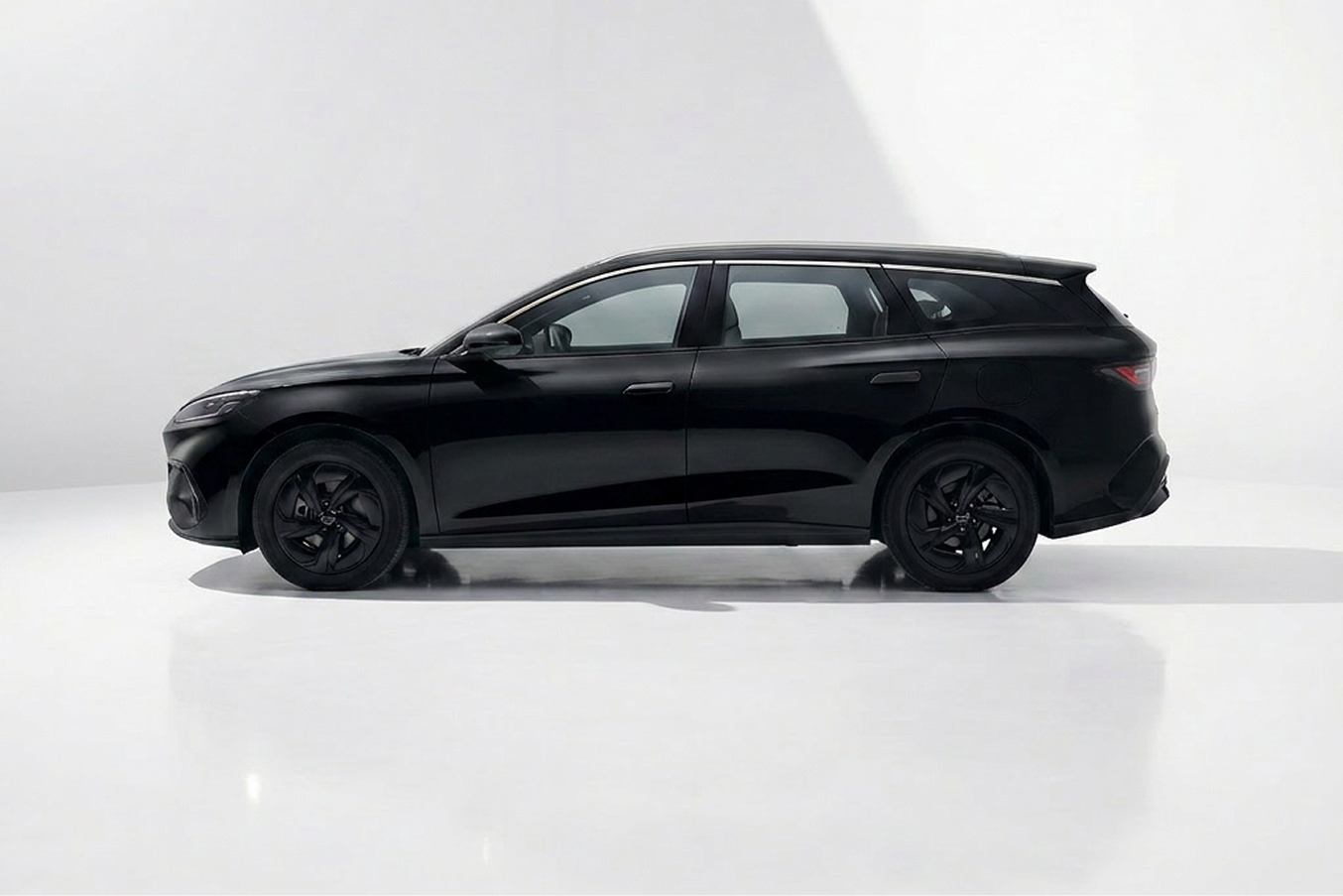 Side view of a sleek black modern station wagon on a white reflective surface.