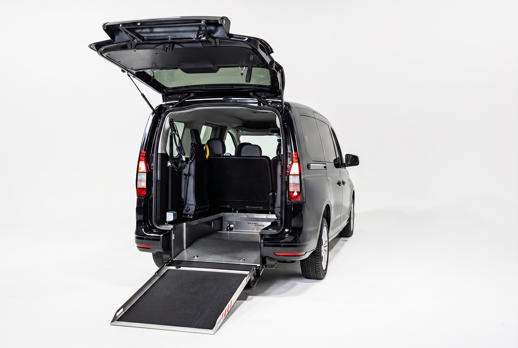 Black van with rear hatch open and wheelchair ramp extended on a white background.