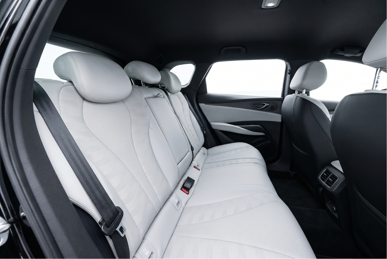 Interior view of luxury car rear seats with light gray leather upholstery and headrests.