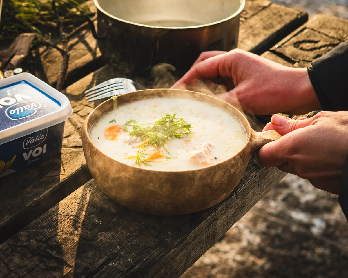 A private Finnish cooking workshop near Helsinki, where guests prepare salmon soup over an open fire in a forest setting. The experience includes guiding, transfers, local storytelling, and time around the fire.