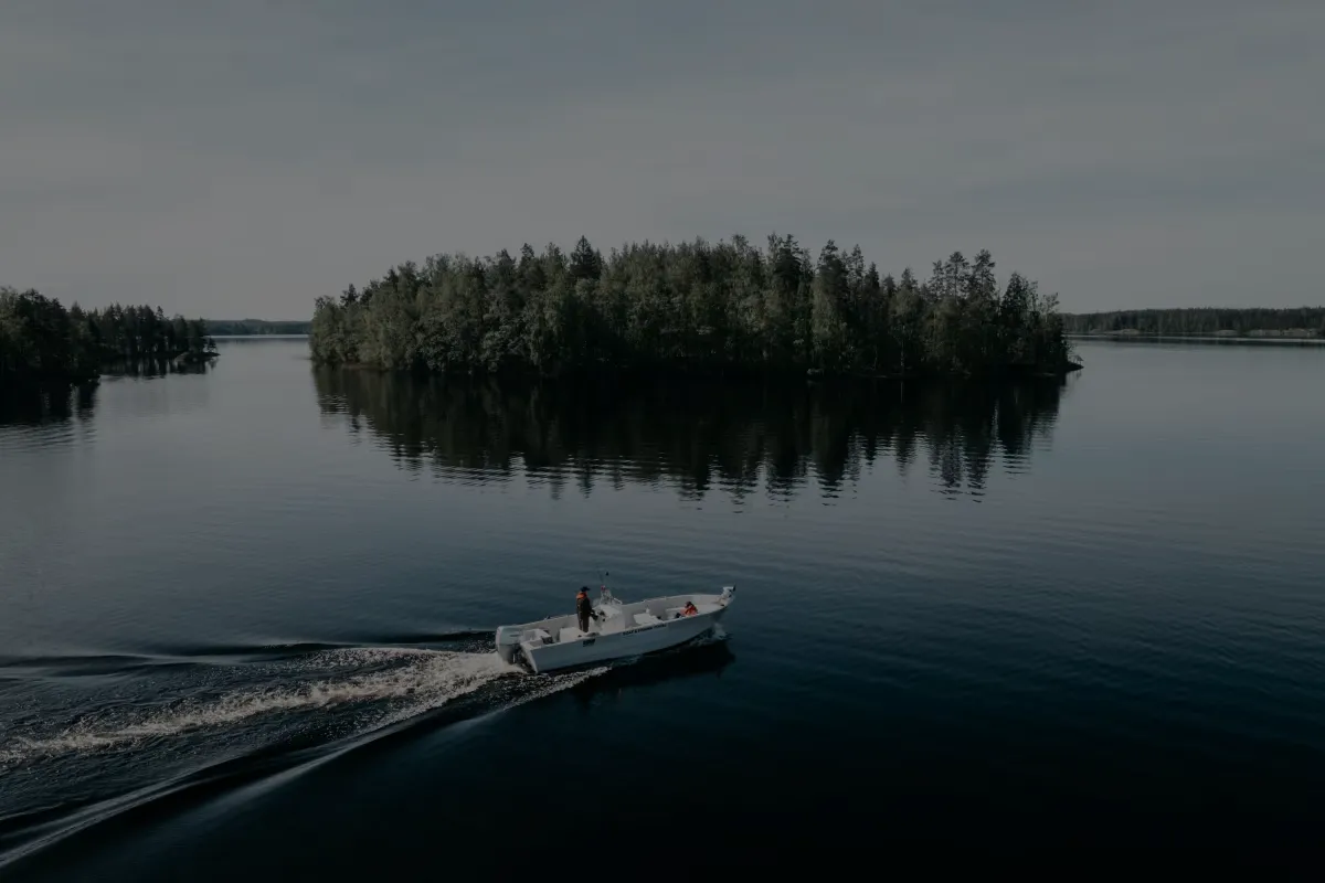 Motorboat crossing a calm lake past a wooded island