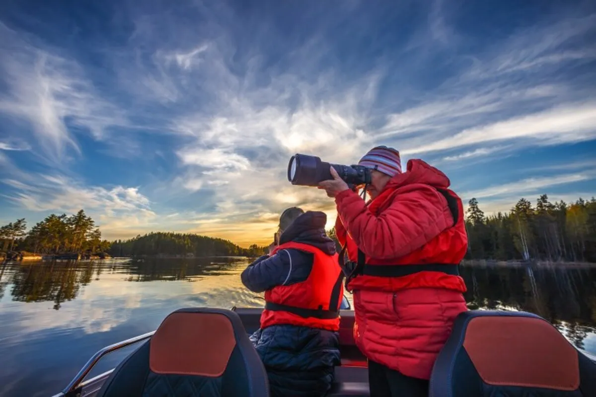 Guests in life jackets taking photos from a boat on Lake Saimaa
