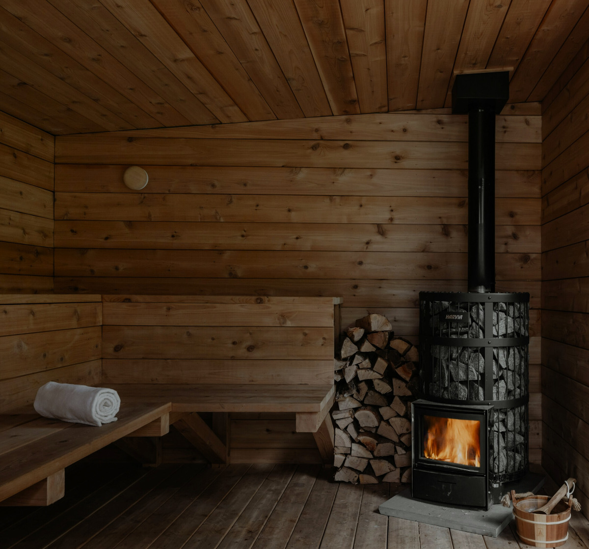 Wood-burning stove and stacked logs inside a timber sauna