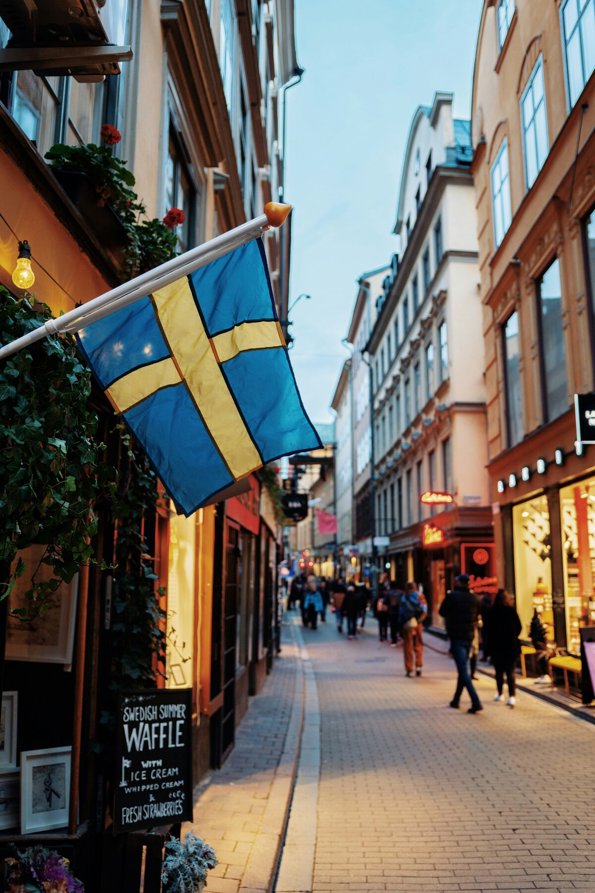 Swedish flag above a busy shopping street in Gamla Stan, Stockholm