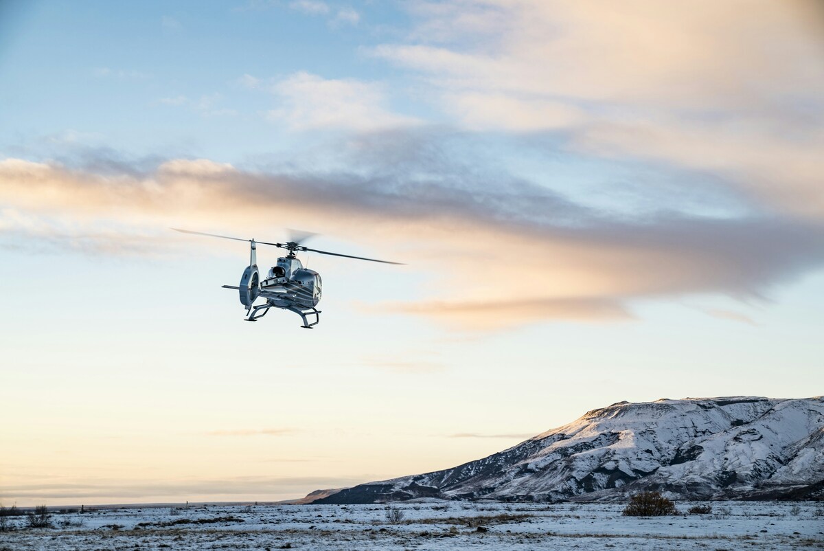 Helicopter flying low over a snowy plain at dawn