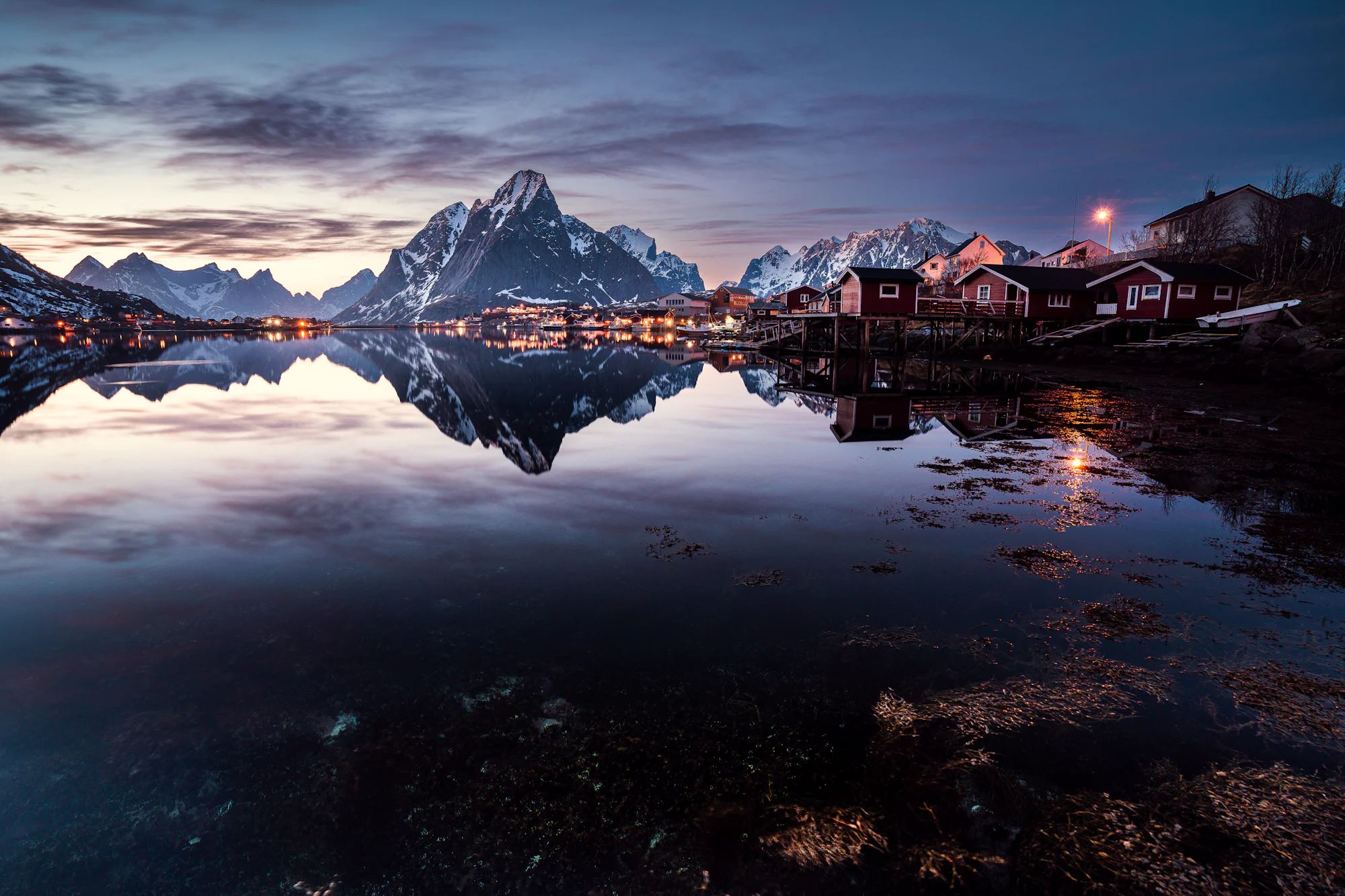 Snow-covered mountains above the calm water of Reine in Lofoten, northern Norway, in winter