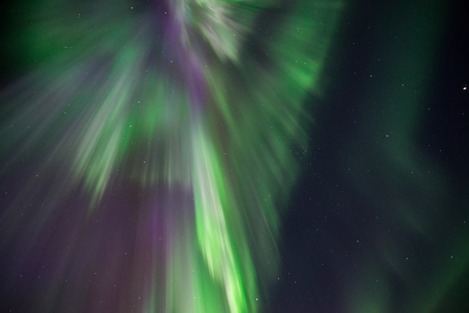 Green and violet Northern Lights across the night sky in Finnish Lapland