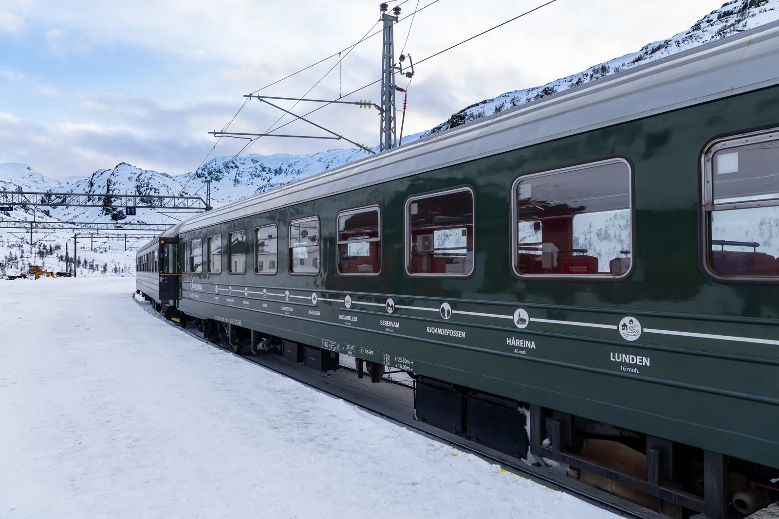Flåm Railway train running through a snowy mountain valley between Myrdal and Flåm, Norway