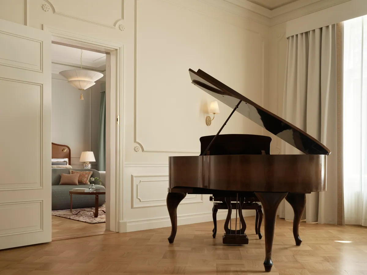 Sibelius Suite with a grand piano and tall windows at Hotel Kämp in Helsinki
