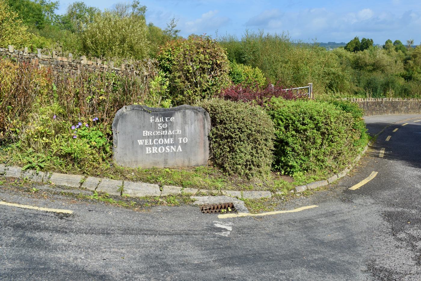 Welcome to Brosna stone sign surrounded by shrubs
