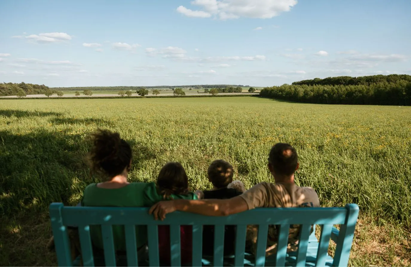 Familiy sat on a bench looking out on a view over the fields at Sycamore and Stars