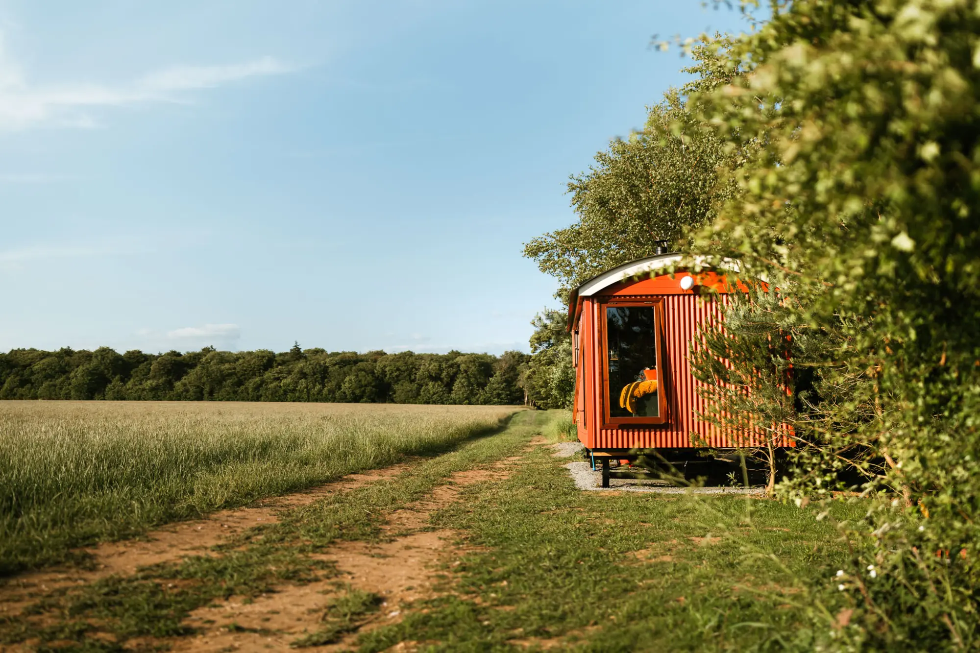 The Badger Sett, a red shepherd's hut at the edge of a field
