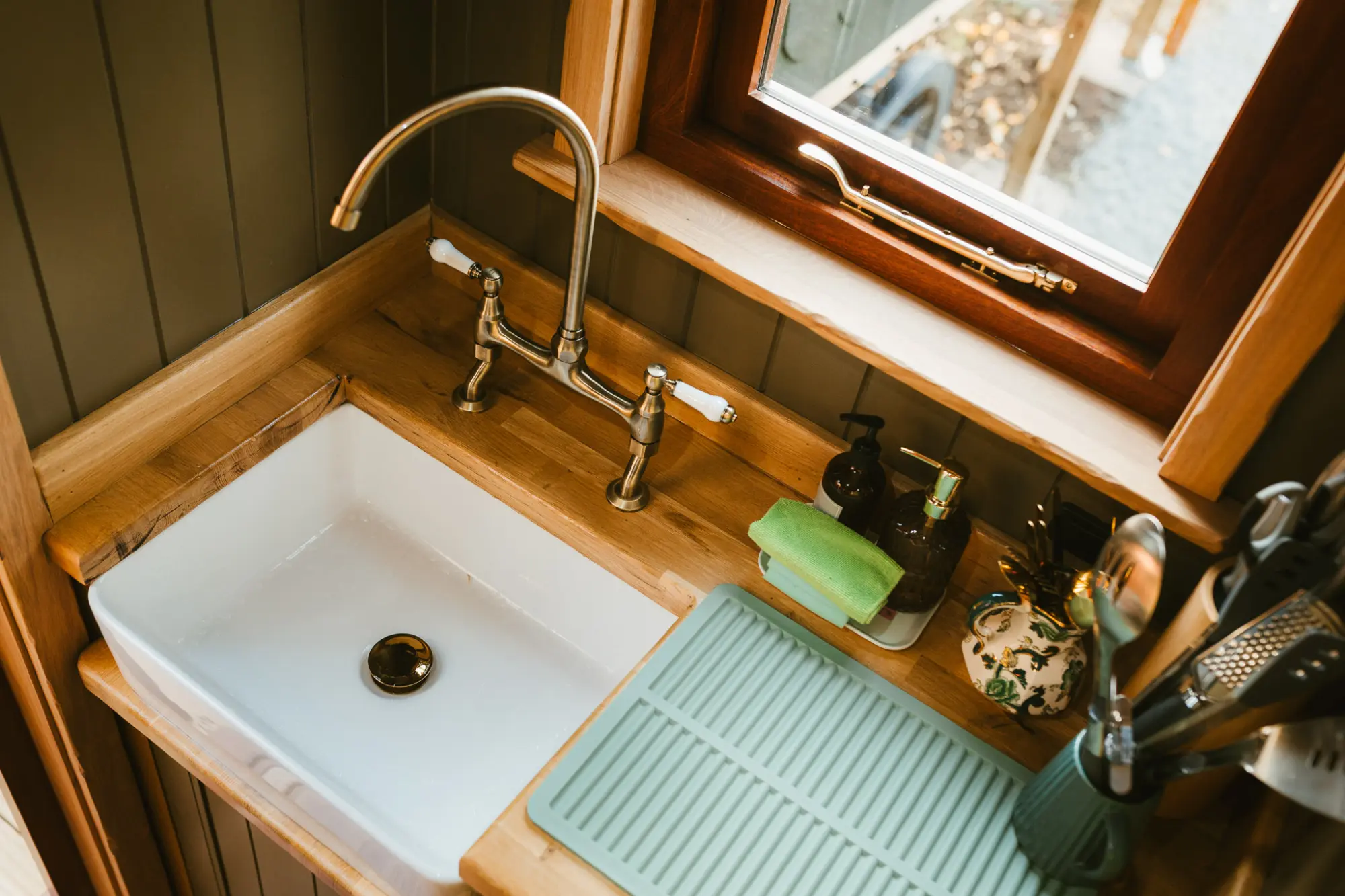 Butler sink and brass tap under the kitchen window