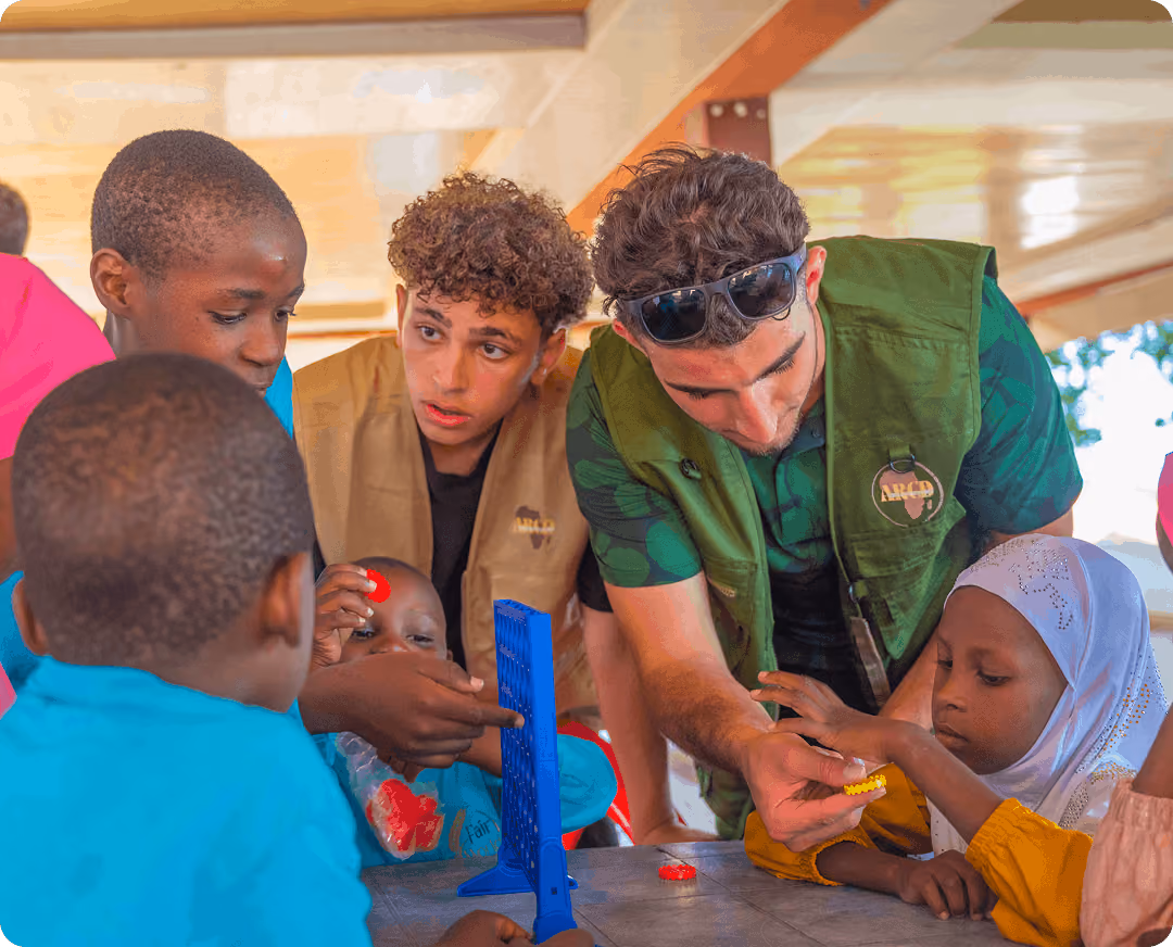 Volunteers interacting and working with young children around a table during an educational activity.