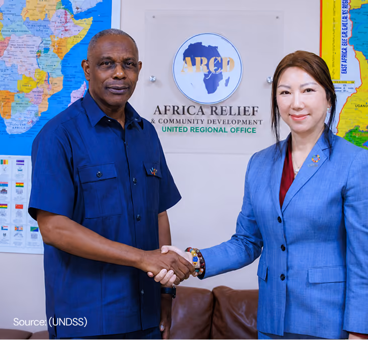 Two organization representatives shaking hands in front of an event backdrop to mark a partnership or milestone.