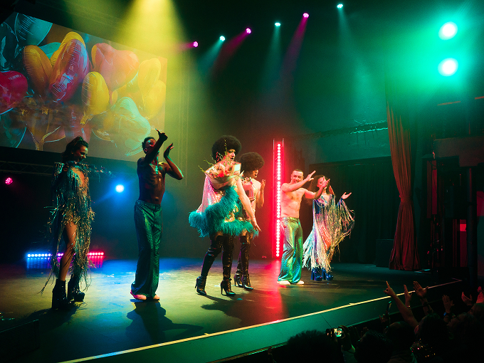 Collective performers on stage with colourful lights