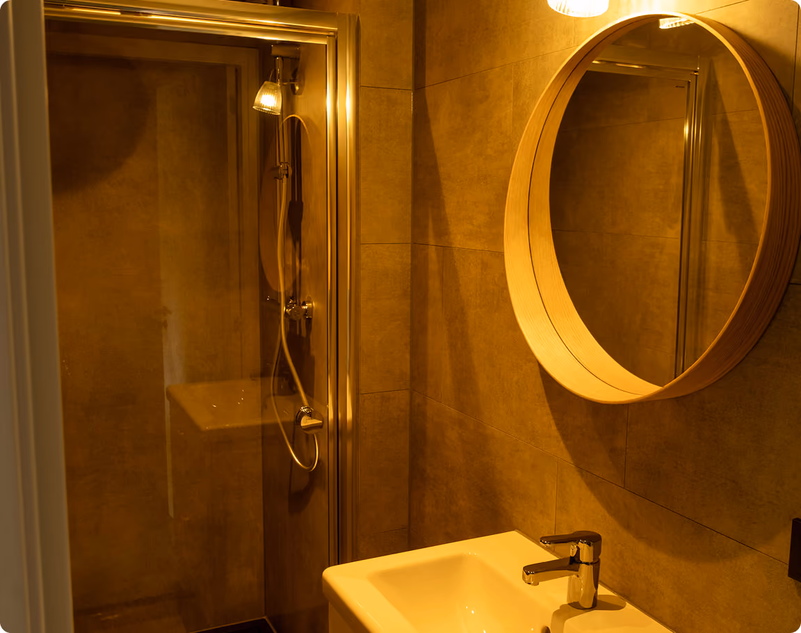 Modern bathroom with a freestanding white bathtub, glass-enclosed shower with rainfall showerhead, wooden vanity, and beige stone tile walls and floor.