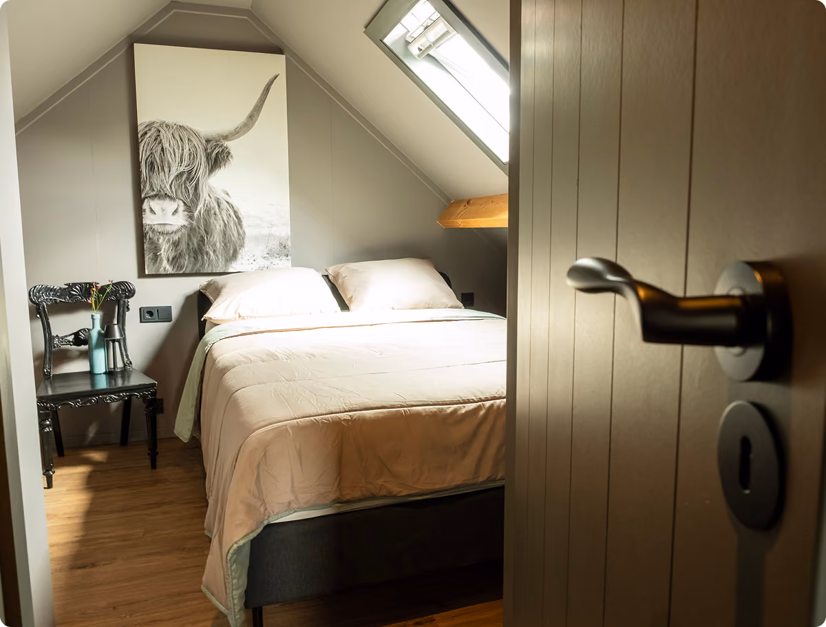 Bright bedroom with large windows showing a river and an apple orchard outside.