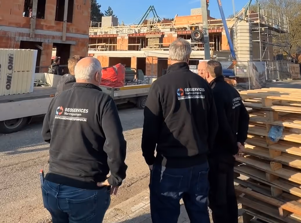 Vier mannen in zwarte jassen met het bedrijfslogo van Geoservices op de rug.