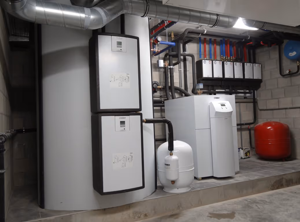 Modern verwarmingssysteem met boilers, leidingen en een rood expansievat.