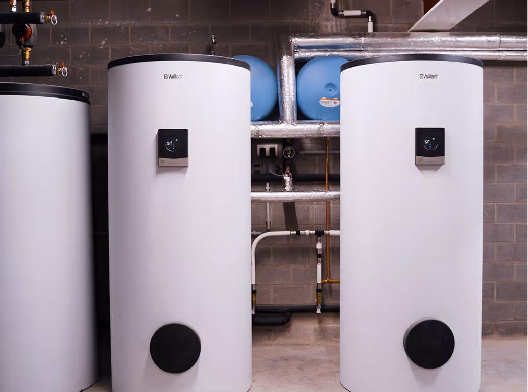 Twee grote witte Vaillant-boilers die via leidingen met elkaar zijn verbonden.