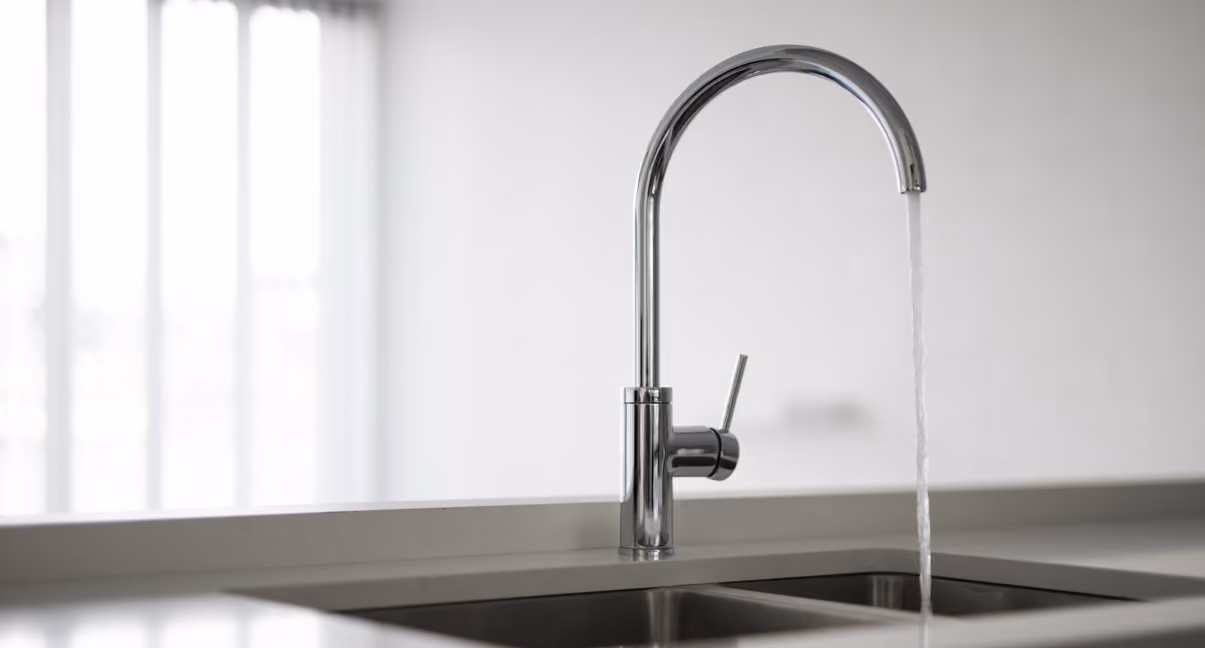 Moderne, chromen keukenkraan met stromend water boven een dubbele spoelbak.
