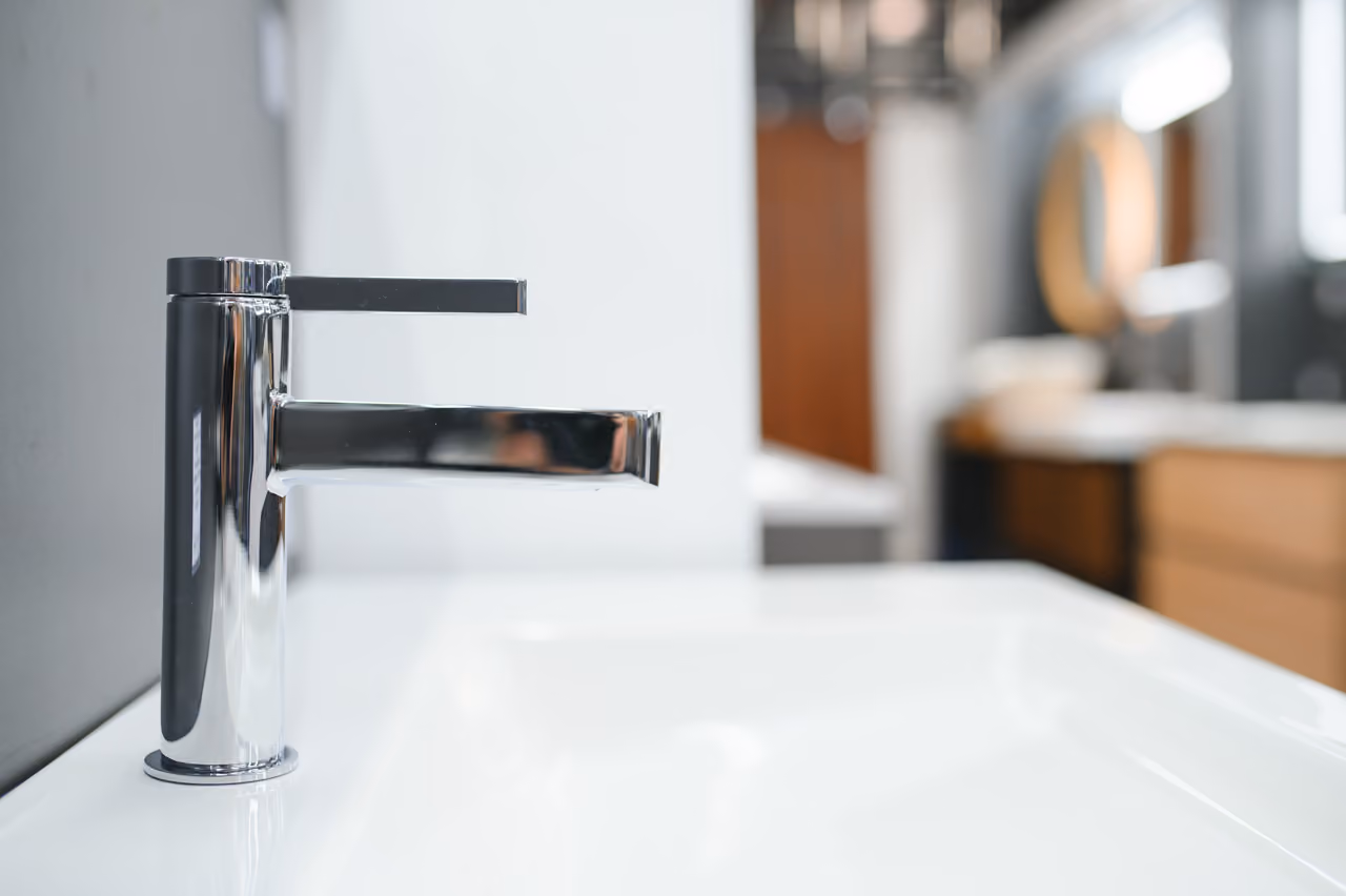 Moderne chromen kraan bij een wasbak in een lichte badkamer.