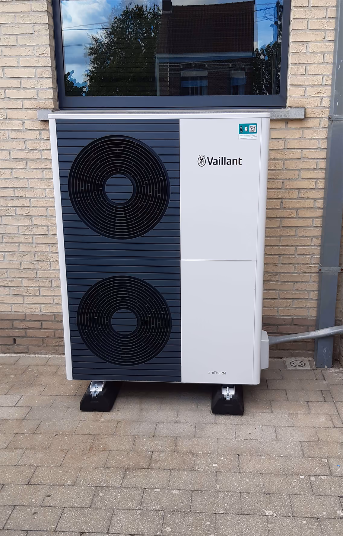 Vaillant aroTHERM warmtepomp buitenunit met twee ventilatoren geplaatst tegen gevel.
