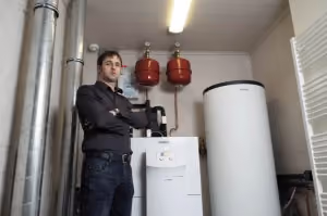 Technieker van Geoservices bij een warmtepomp met buffervat in een technische ruimte