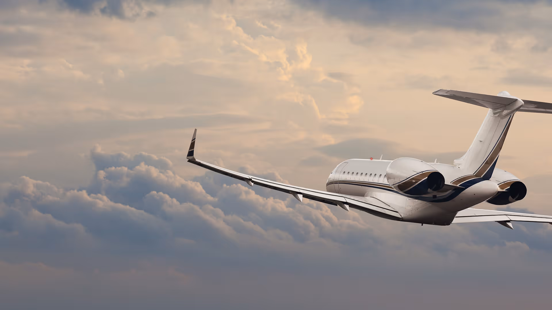 Private jet flying above dense clouds with a pastel-colored sky in the background.
