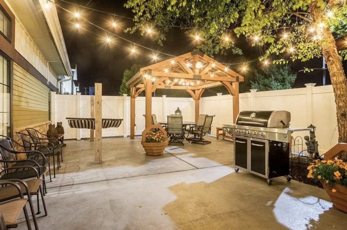 A patio with a grill and outdoor furniture at night. Experience Holland, MI: Fun Places to Stay and Explore.