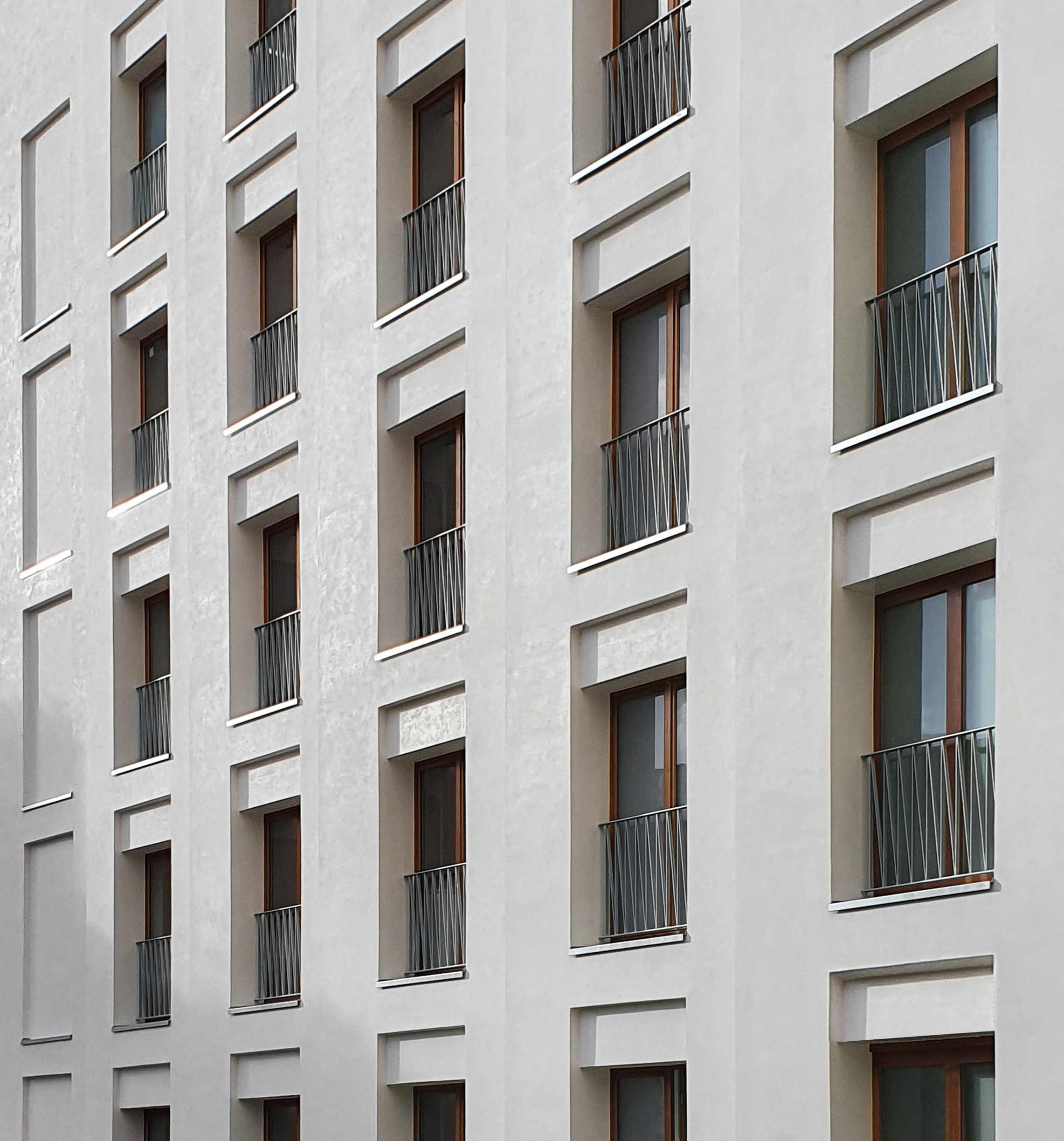 Façade d'immeuble blanc avec plusieurs fenêtres équipées de garde-corps métalliques.
