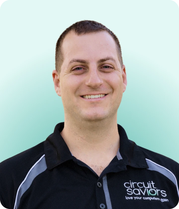 Smiling man wearing a black Circuit Saviors polo shirt with a green gradient background.