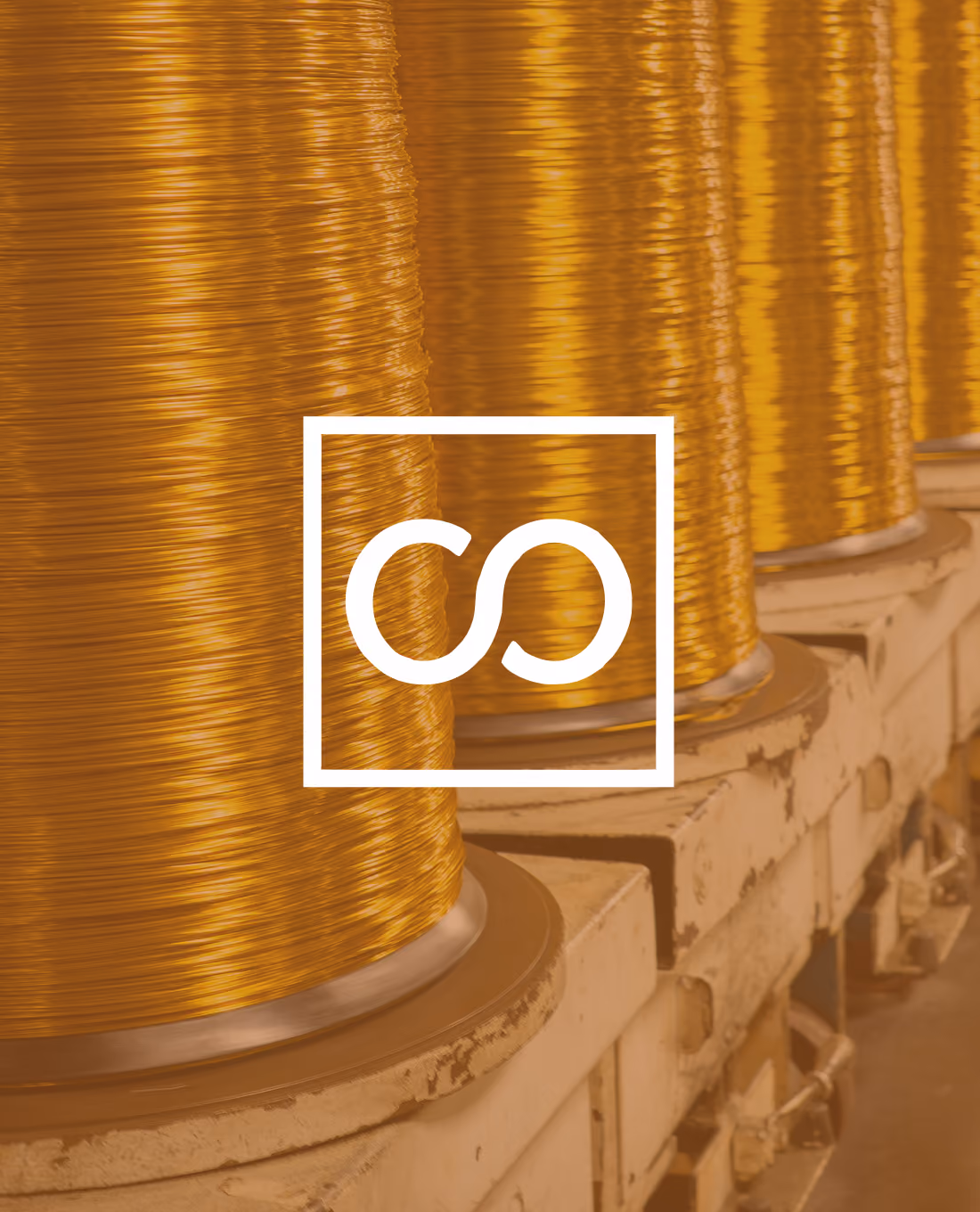Spools of shiny copper wire lined up on industrial machines in a factory setting.