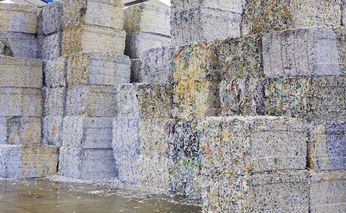 Stacks of compressed, shredded paper bales ready for recycling in a warehouse.