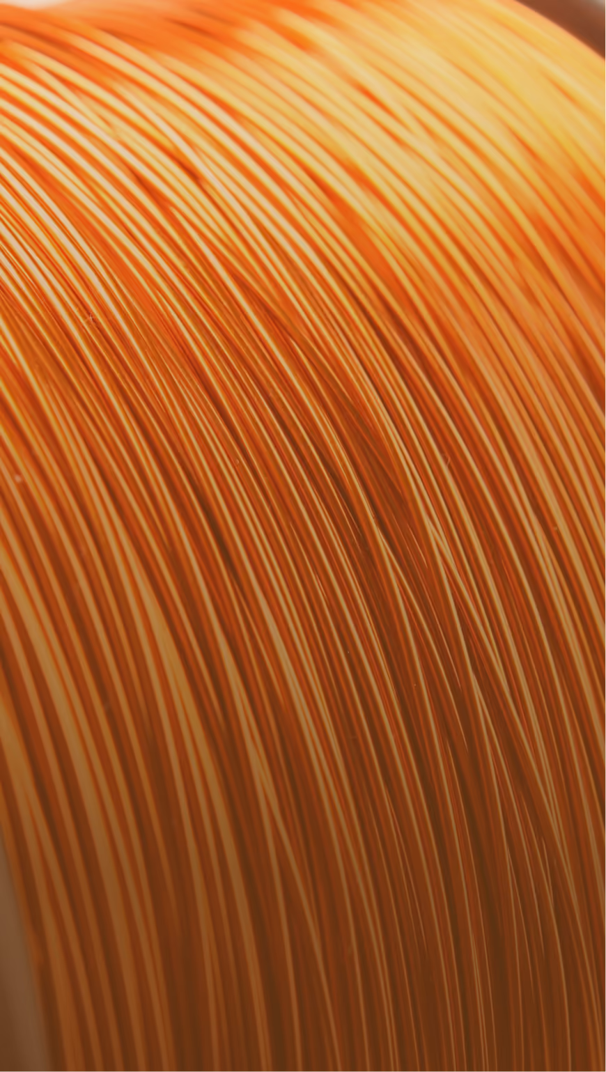 Close-up of tightly coiled copper wire strands with an orange metallic sheen.