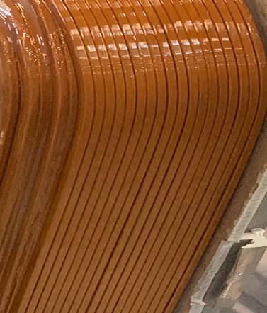Close-up of tightly wound orange copper wire coils in an industrial setting.
