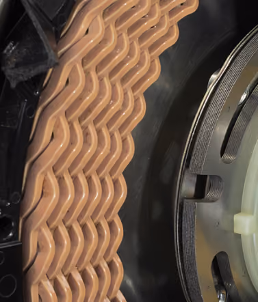 Close-up of repetitive tan interlocking parts inside circular mechanical device.
